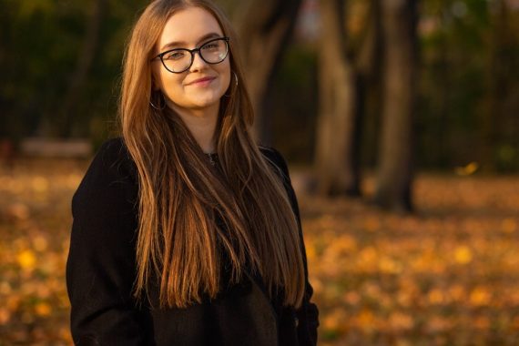 a woman wearing glasses standing in a park
